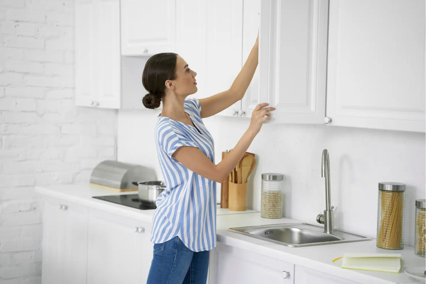 Woman looking in white cabinets in a kitchen | California Renovation
